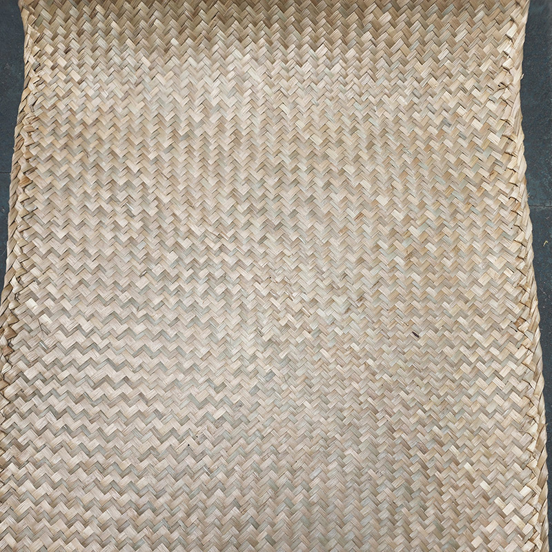 Seagrass sheet weaving detail showing natural greenish straw hue and colored border accents